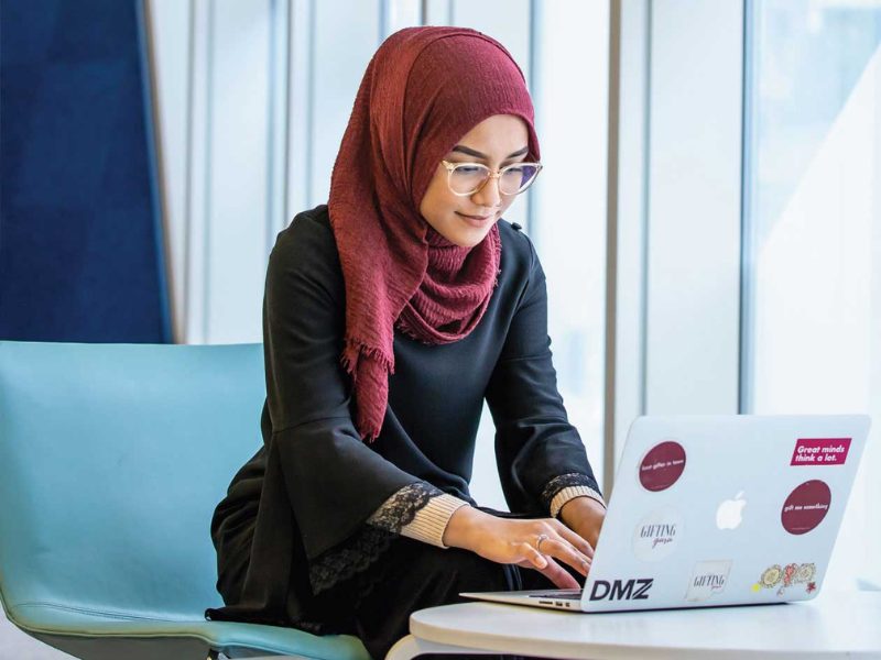 Female graduate student sitting in SLC typing on laptop