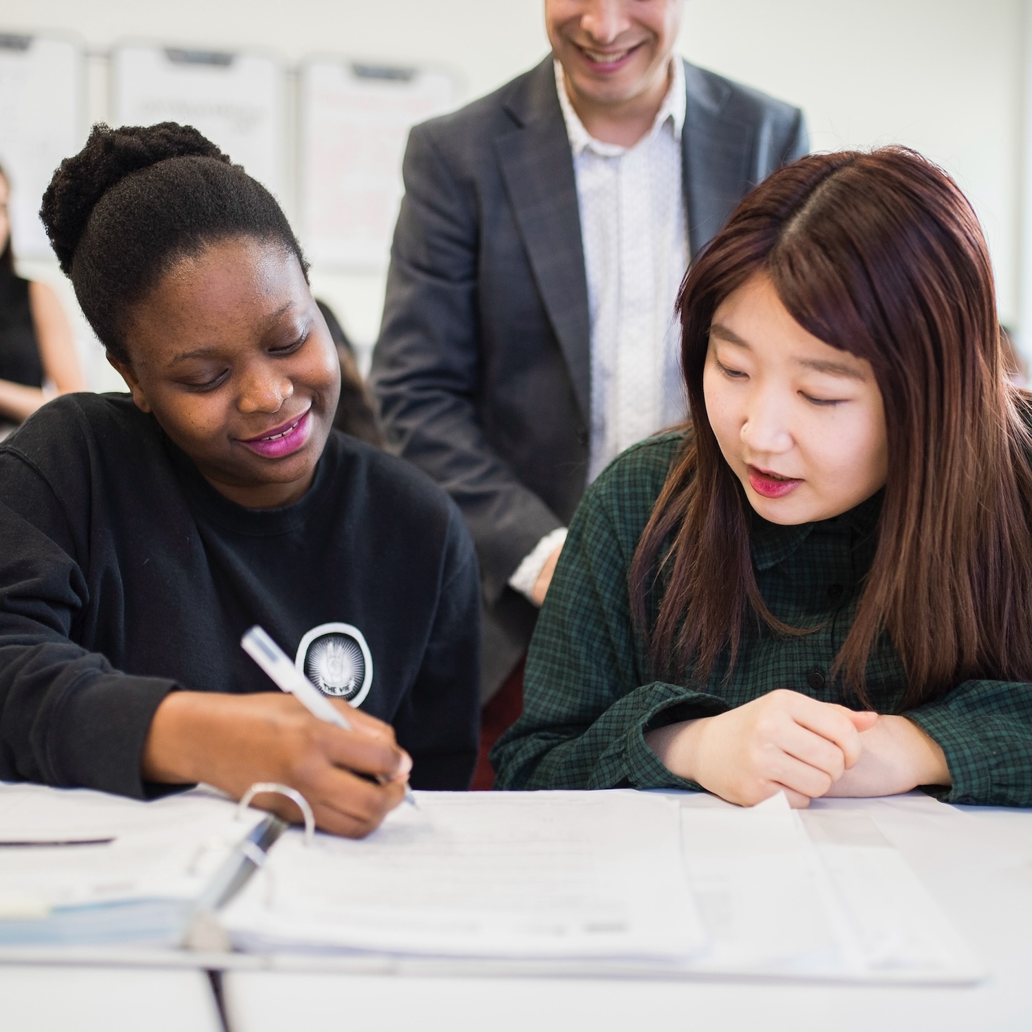 Two students at the ELI studying with instructor in the background