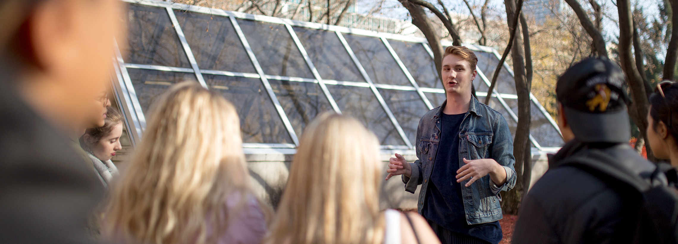 A student tour guide speaking at the Quad to guests touring the TMU campus.