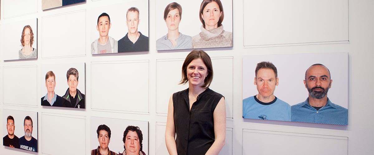 Graduate student standing in front of a wall mural, showcasing headshots