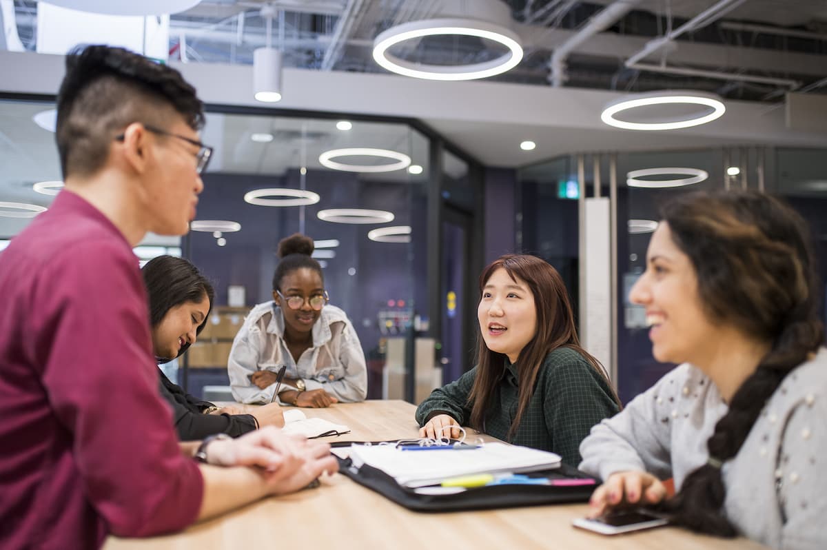 Students engaged in conversation around a table in the ELI lounge