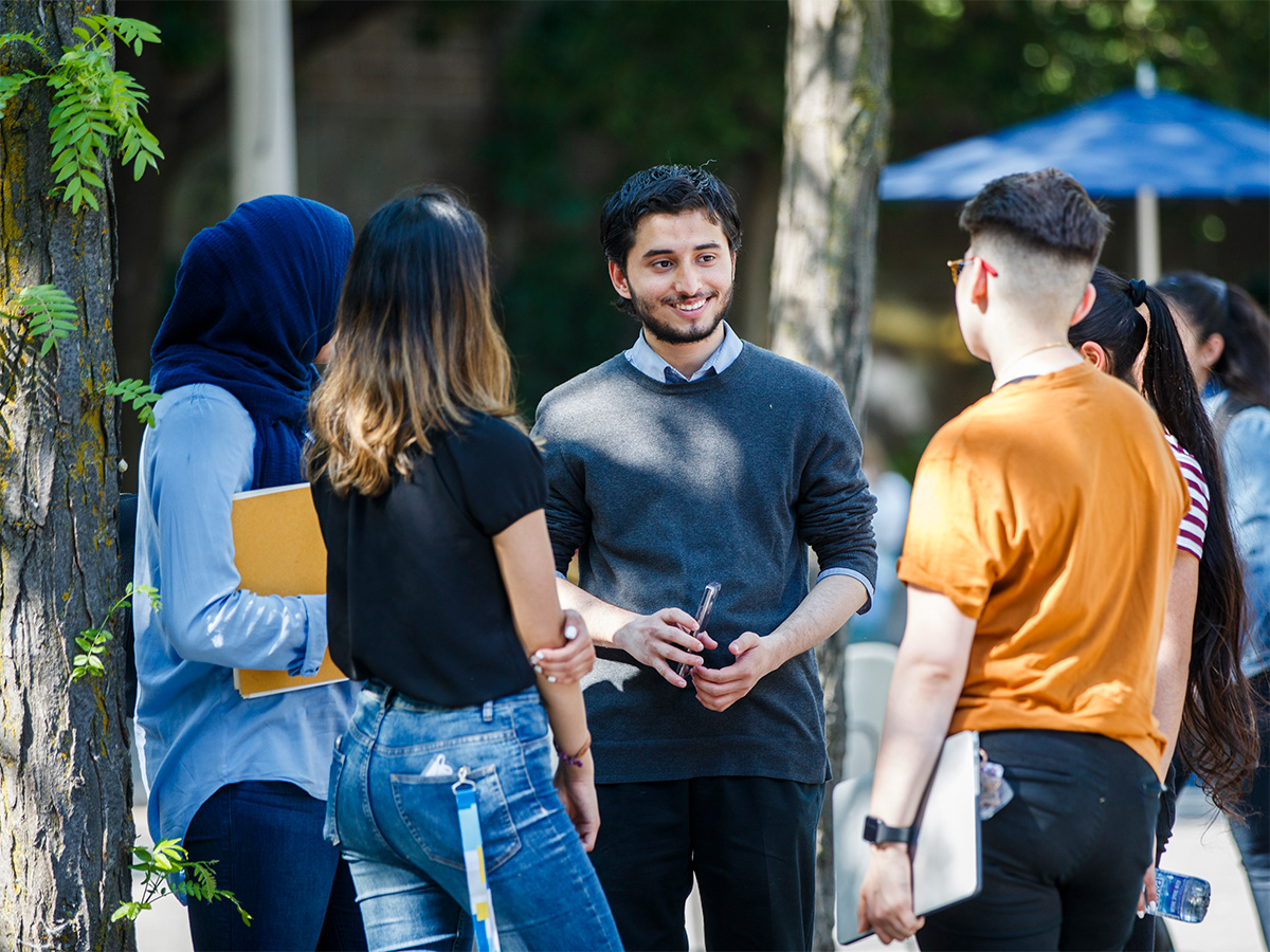 A group of students outside of the Image Arts Centre talking amongst each other.