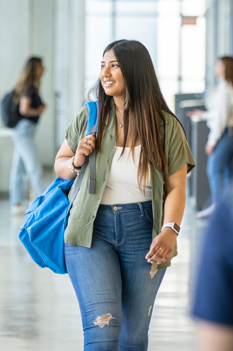 Student holding a backpack walking through the hallways of TMU