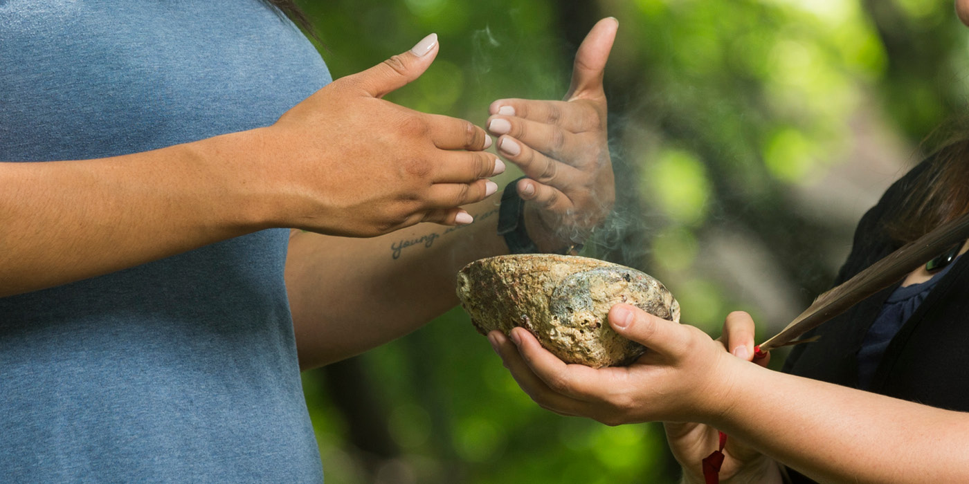 Two people participating in smudging in the Quad.