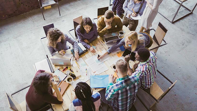 Students collaborating and working at a wooden table