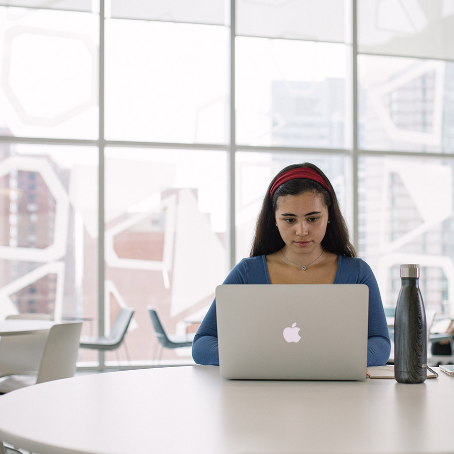 A student on a laptop concentrates on her work.