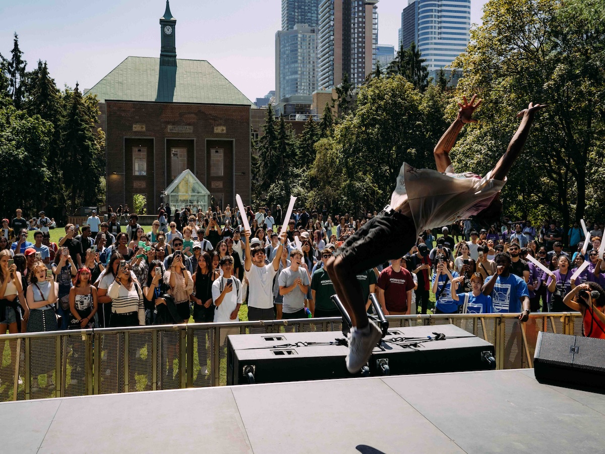 Students cheering for a performer doing a backflip on the Orientation Week stage