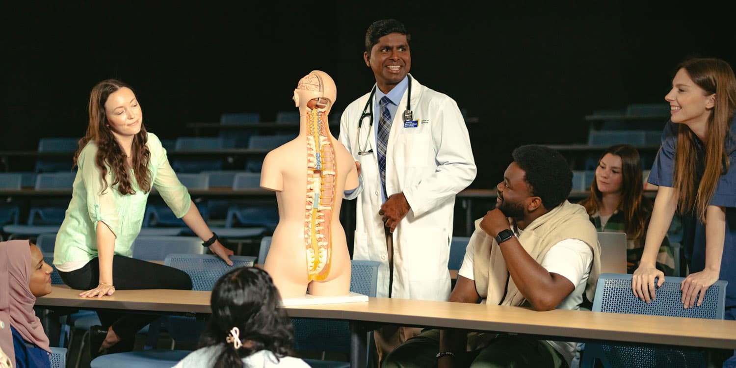 A male physician teaches a group of students using an anatomy model