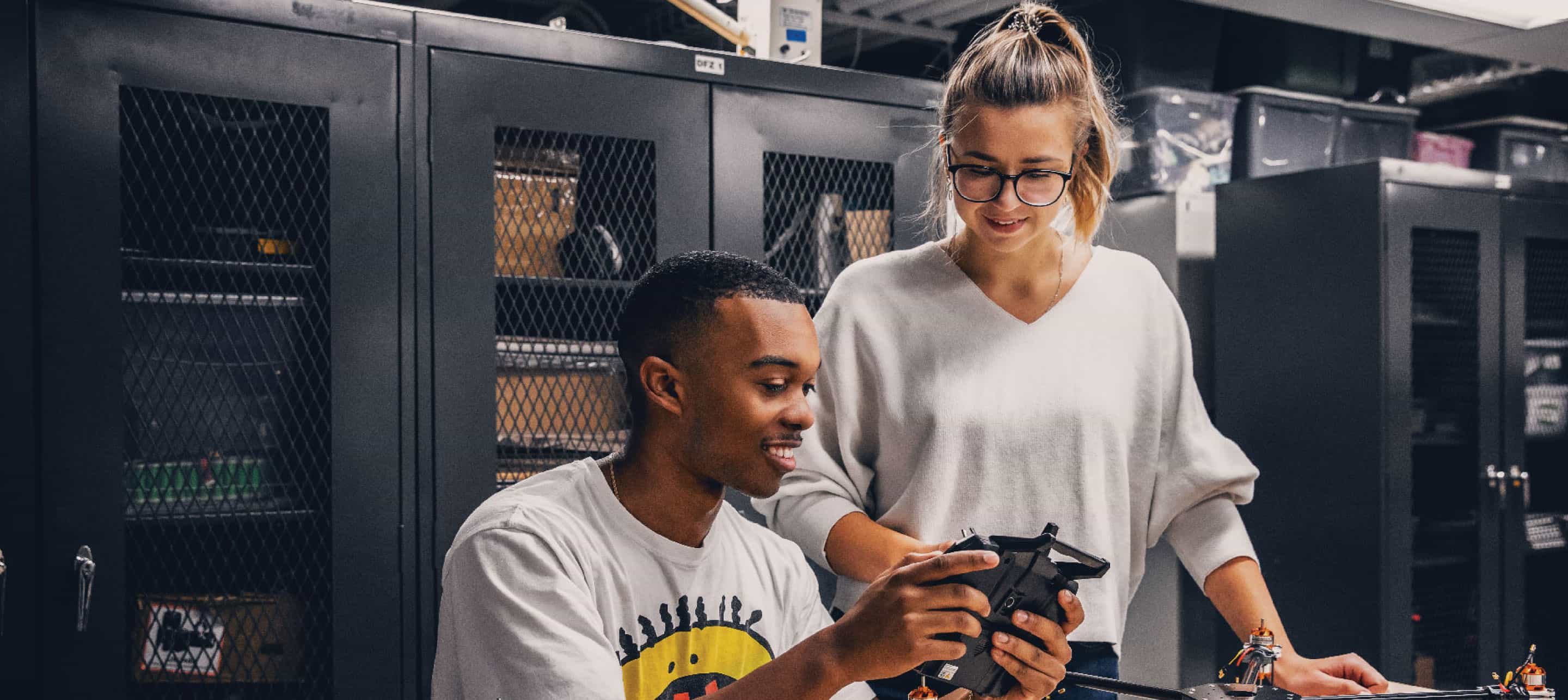 two students in a lab setting looking at a gadget