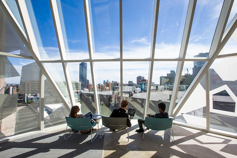 Three students, sitting with their backs to the camera, looking out a window in the Student Learning Centre