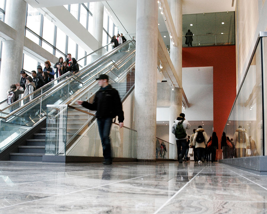 Students walking through the halls of TRSM. Additional students can be seen on the escalator in the background.