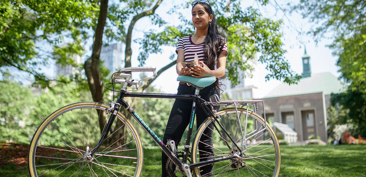 TMU student resting her arms on the seat of her bike, in the TMU Quad.