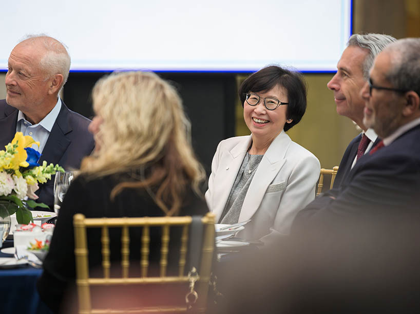 The Chancellor is smiling warmly alongside university staff and administration at a table during the Emerita dinner.