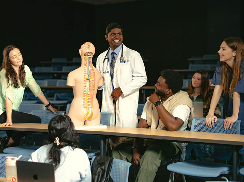 A male physician teaches a group of students using an anatomy model.