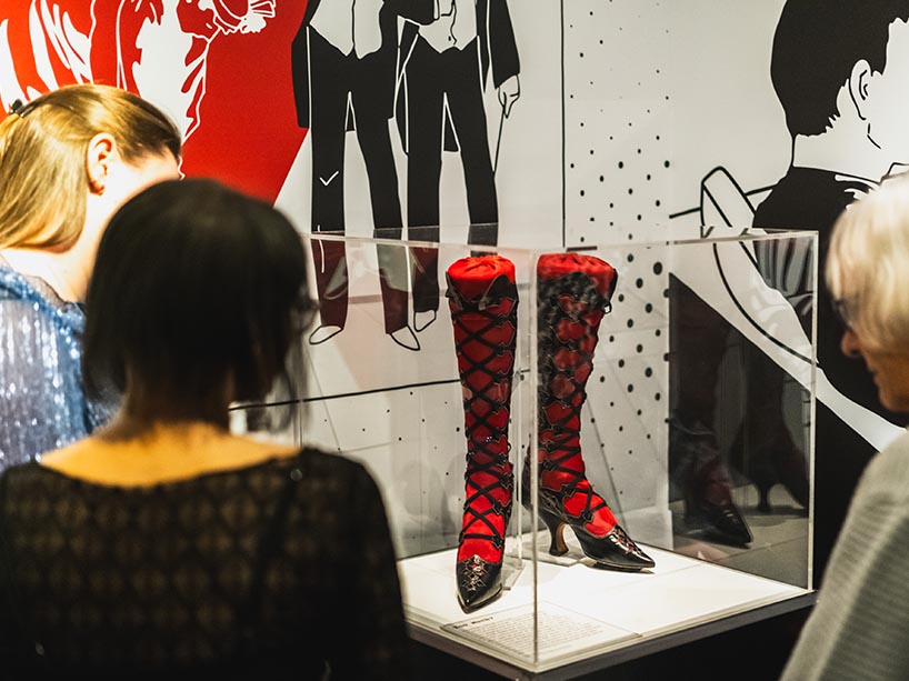 A patron looking at a museum exhibit of shoes. 