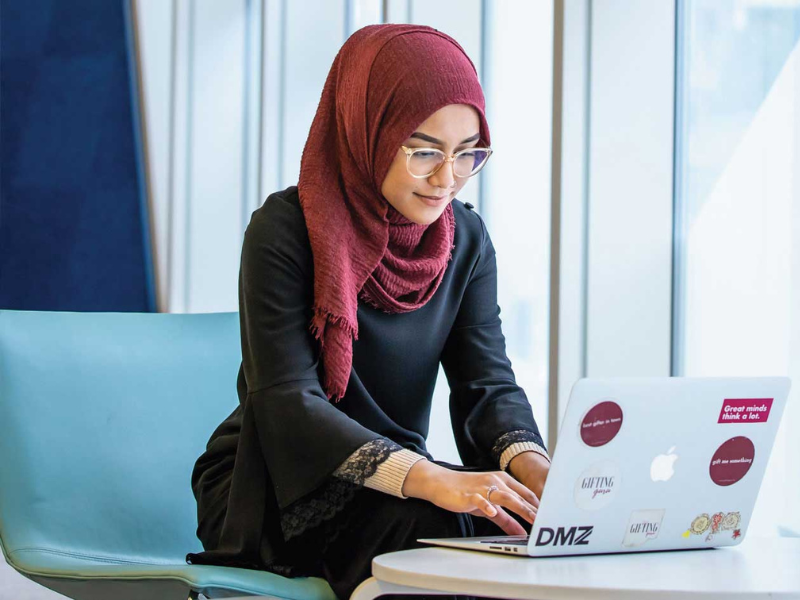 Student studying with laptop in SLC building.